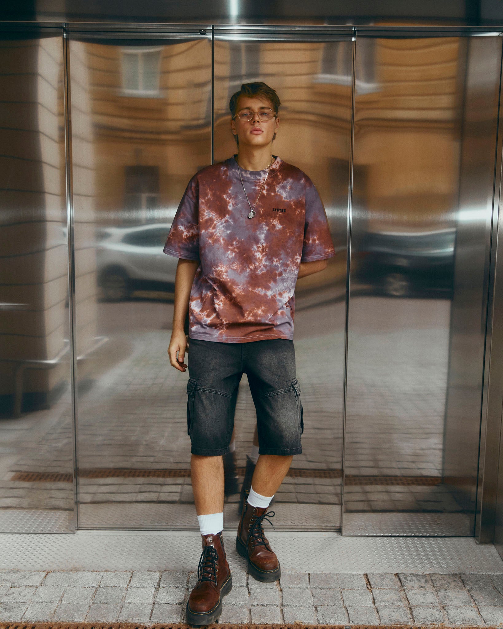 A short-sleeve crewneck t-shirt featuring a brown and grey tie-dye pattern, with a small black 'LISTEE' text logo printed on the left chest, displayed flat against a light gray background.