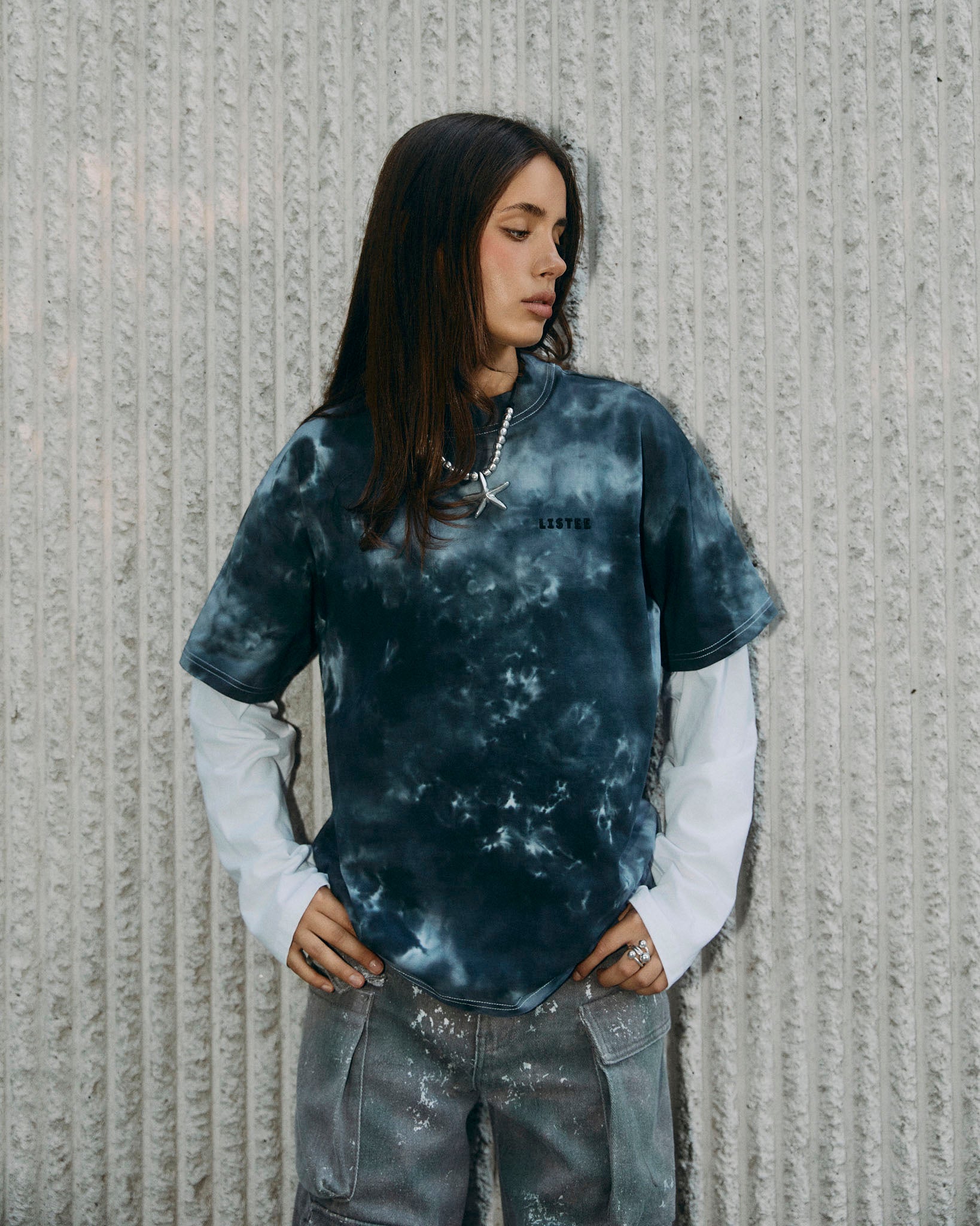 A short-sleeve oversized crewneck tie-dye t-shirt featuring a black and grey pattern, laid flat against a light gray background.