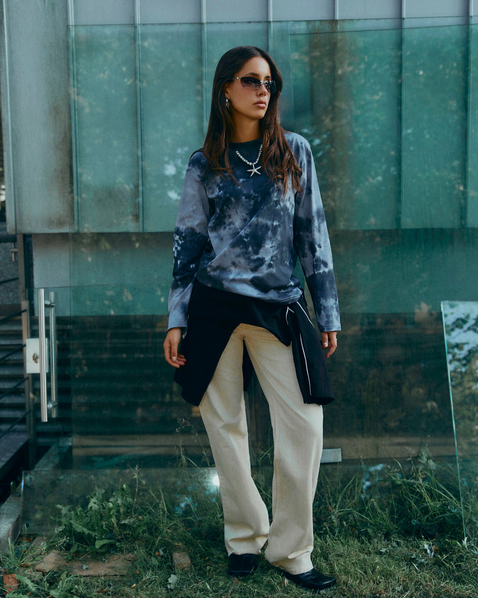 A long-sleeve crewneck shirt featuring a dark gray and black tie-dye pattern, with a small black 'LISTEE' logo on the chest, displayed flat against a light gray background.