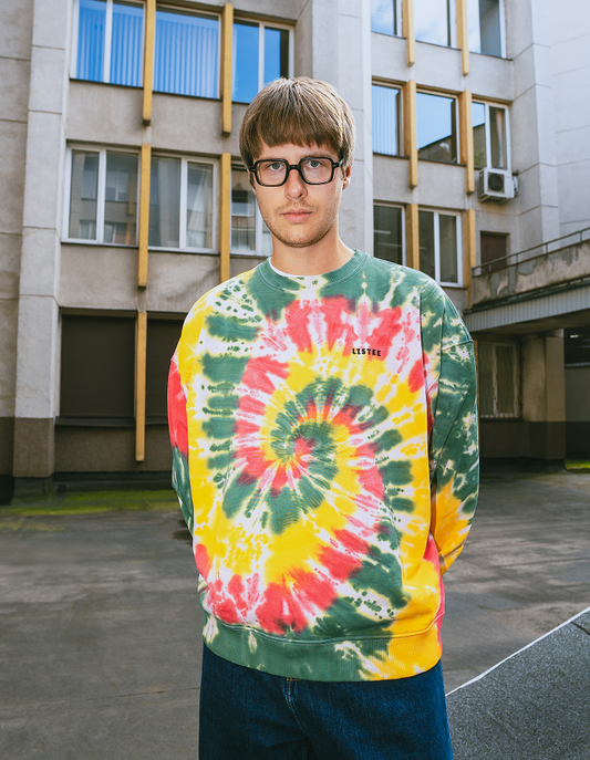 Person wearing a tie-dye sweatshirt in front of a building
