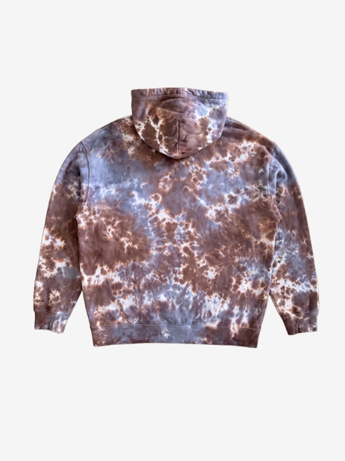 A tie-dye hoodie shown from the back, featuring a marbled pattern of brown, grey, and white, photographed against a solid off-white background.